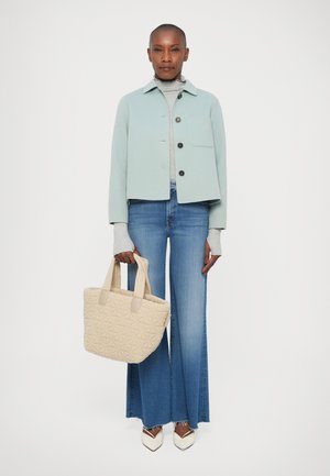 Lichtblauwe cropped jas, grijze coltrui, uitlopende blauwe jeans, gestreepte beige handtas en witte puntige hakken.