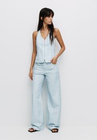 Top senza maniche a strisce celesti, con scollatura a V e dettagli con bottoni, abbinato a pantaloni larghi coordinati. Tessuto morbido, design casual.