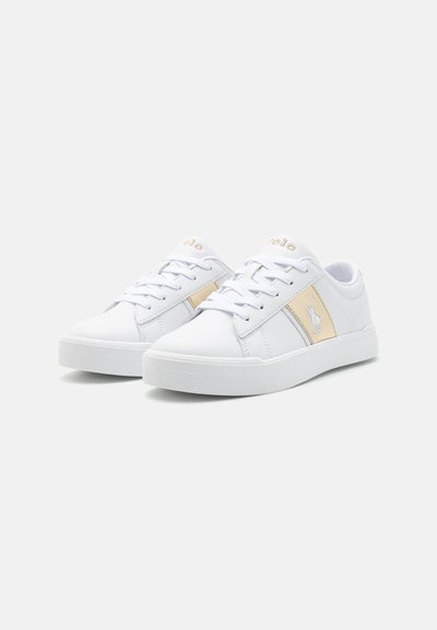 Vita sneakers med en slät yta, med beige accenter, snörning framtill och subtil logotypdetalj på sidan. Gummisula för bra grepp.