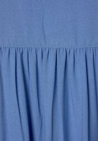 Blauer Stoff mit subtiler Textur, der an der Unterseite zusammengeführte Falten und eine glatte Oberfläche aufweist. Keine zusätzlichen Muster oder Akzente vorhanden.