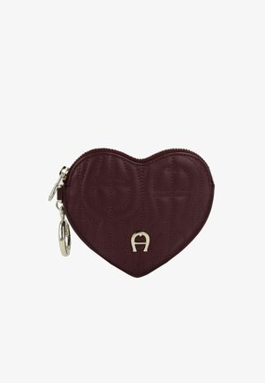 Bordeauxrode leren portemonnee in hartvorm, gestikte textuur, rits en hardware in goudkleur, met een decoratief logo-accent aan de voorkant.