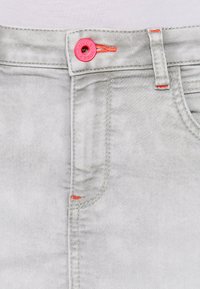 Hellgrau denim Rock mit einem Knopfverschluss, einem leuchtend rosa Akzent und orangen Nähten in der Nähe der Taschen.