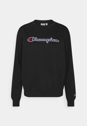 Sudadera negra de manga larga con cuello redondo, con el logo "Champion" en blanco y rojo en el pecho y un logo pequeño en el puño de la muñeca izquierda.