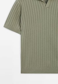 Pull en tricot vert olive à manches courtes avec des côtes verticales et un détail subtil de col en V.