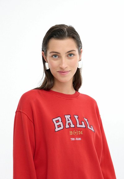 Rød sweatshirt med oversized pasform, ribbet rundhals og broderet "BALL 1974 THE JEANS" grafik. Har en glat stoftekstur.