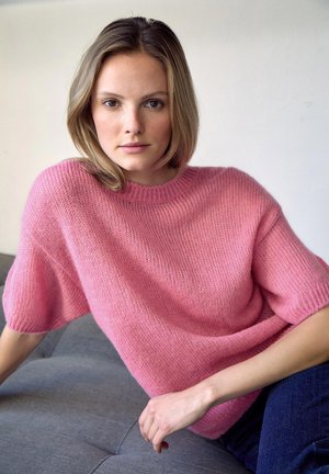 Pull en tricot rose clair avec une coupe décontractée, des manches courtes et un col rond, présentant une texture douce et un détail de couture visible.