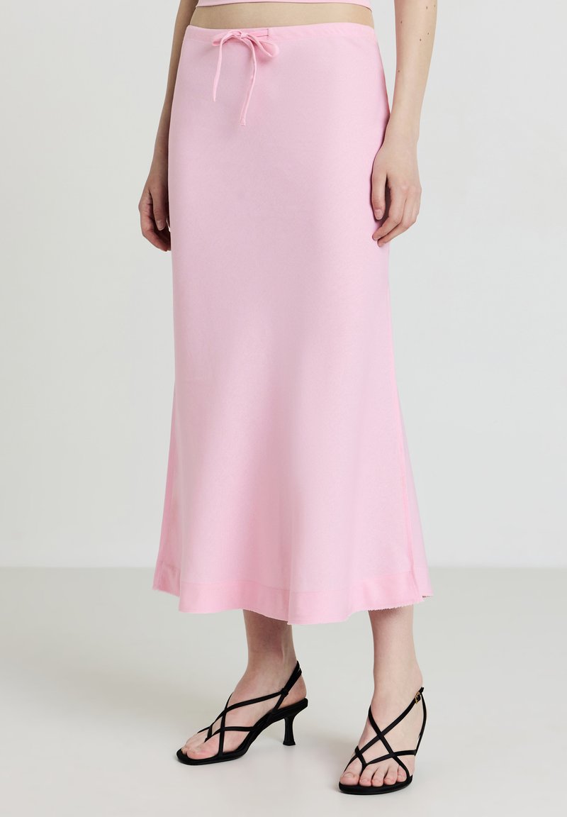 Helles rosa Midi-Rock aus weichem Stoff, mit einem elastischen Bund mit Kordelzug und einer ausgestellten Silhouette. Enthält schwarze Riemchenabsätze.