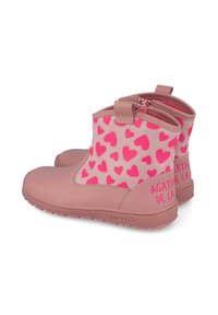 Botas de tobillo impermeables en color rosa con un patrón de corazones, que cuentan con un cierre de cremallera y un detalle de marca, hechas de un material suave.