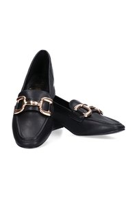 Mocasines de cuero negro con punta afilada, que presentan un acento de cadena dorada en la parte frontal y un tacón bajo y plano. Textura suave.