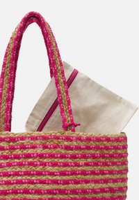 Sac cabas en paille tissée avec des rayures roses et naturelles, doté de poignées tressées et d'une pochette crème avec une fermeture éclair rose à l'intérieur.