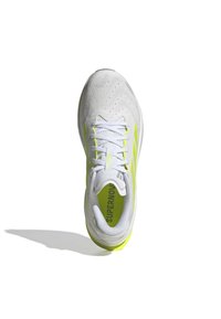 White running shoe with yellow accents, breathable mesh upper, textured surface, and a cushioned sole. Features prominent "SUPERNOVA" branding.