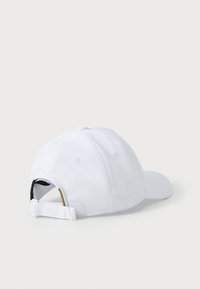 Hvit baseballcaps med strukturert krone, buet skjerm og justerbar stropp bak. Laget av teksturert stoff med ventilasjonshull.