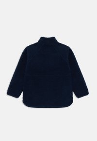 Marineblauer Fleece-Pullover mit hohem Kragen, Raglanärmeln und einer strukturierten, samtigen Oberfläche. Abgerundeter Saum ohne sichtbare Verschlüsse.