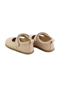 Zapatos Mary Jane de cuero rosa claro con puntera redonda, bordes en forma de ola y una correa de velcro; suela de goma color marrón. La vista trasera muestra un forro suave.