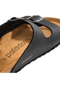 Ciabatta nera con cinturini testurizzati, una soletta in sughero naturale e un accentuato cinturino metallico. Nome del marchio "palado" impresso all'interno.
