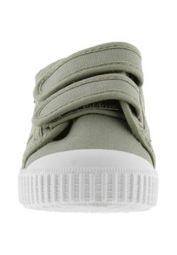 Vue de face d'une sneaker en toile vert clair avec une semelle en caoutchouc blanche et deux sangles Velcro.