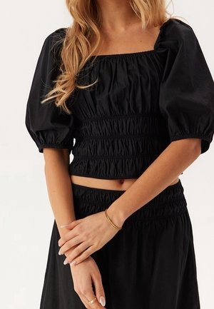 Schwarzes kurz geschnittenes Oberteil mit quadratischem Ausschnitt, Puffärmeln und elastischen Rüschen. Verfügt über eine glatte, weiche Stofftextur.