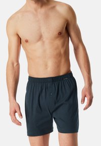 Boxer in cotone navy scuro da uomo con elastico in vita, dotati di un bottone frontale e una vestibilità rilassata, realizzati in morbido tessuto traspirante.
