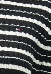 Πλεκτό πουλόβερ με ριγέ σχέδιο σε ασπρόμαυρο και υφή ριμπ. Διαθέτει εναλλασσόμενες ρίγες σε ανοιχτό γκρι, λευκό και μαύρο χρώμα, με μπαλώμα λογότυπου.