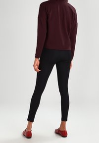 Burgundin värinen, teksturoitu pitkähiha, yhdistettynä tiukkoihin mustiin legginsseihin ja punaisiin ballerinoihin. Asusteessa on rento takatyyli.