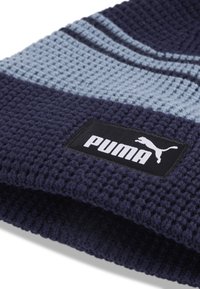 Gebreide beanie in marineblauw en lichtblauwe strepen, met een gemêleerd patroon en een zwart rechthoekig label met het witte "PUMA" logo.