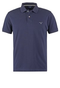 Polo bleu marine à manches courtes avec col, patte à deux boutons et petit logo blanc GANT sur la poitrine gauche.