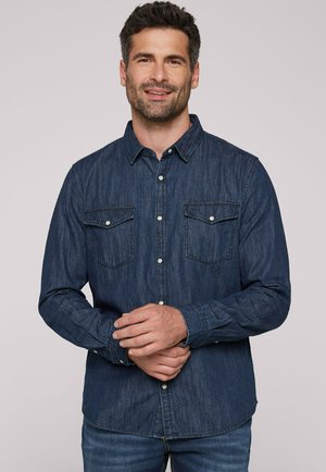 Denimhemd, dunkelblau, lange Ärmel, durchgehende Knopfleiste, zwei Brusttaschen, subtile Textur, klassischer Kragen, kombiniert mit Jeans.