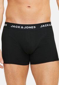 Zwarte katoenen boxershorts met een brede elastische tailleband met het "JACK & JONES" logo in het wit. Glad materiaal, met een lengte tot halverwege de dij.