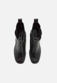Svarta läderankelboots med dragflikar, elastiska sidopaneler, fyrkantig tådesign och mjukt texturerad inre foder.