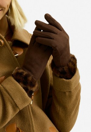 Gants marron avec une texture douce semblable à du daim, dotés d'une manchette en fourrure pelucheuse. Complétés par un manteau tan avec des accents en cuir.