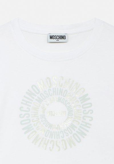 T-shirt blanc pour enfant avec col rond, avec texte en cercle concentrique "Moschino" en lettres brillantes et une étiquette de marque Moschino à l'intérieur du col.