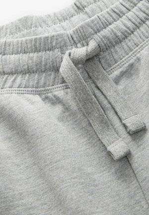 Pantalons de survêtement en coton gris avec une taille élastique et un cordon de serrage. Le tissu a une texture douce et une finition lisse, avec des détails de couture visibles.