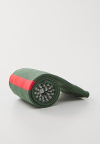 Grüner, gerollter Socken mit einem roten Streifen und einem gemusterten Bündchen, auf einem schlichten weißen Hintergrund.