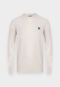 Pull beige clair en maille douce, avec un col rond et des manches longues. Comprend un petit logo brodé noir et or sur la poitrine.