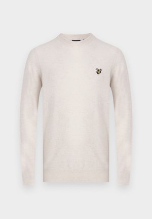 Suéter de un beige claro en suave tejido de punto, con cuello redondo y mangas largas. Incluye un pequeño logo bordado en negro y dorado en el pecho.