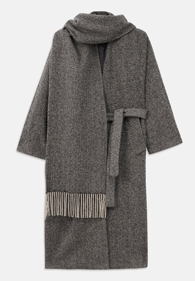 Manteau gris à motif en chevrons, avec des manches larges, une taille nouée et une écharpe assortie avec des franges à la fin.