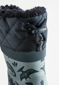 Wodoodporne gumowe buty z szarym korpusem, z czarnymi sylwetkami zwierząt. Góra ma pikowany granatowy kołnierz i regulowane sznurówki.