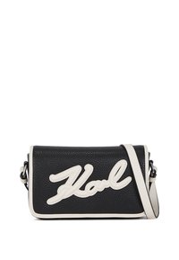Black leather crossbody bag with a textured finish, featuring a white cursive "Karl" logo and contrasting white trim. Adjustable strap included.