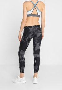 Black and gray marbled leggings with a fitted design, paired with a gray and blue cross-back sports bra and white sneakers.