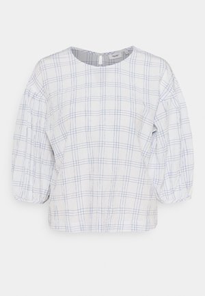 Camicia bianca con motivo a quadri azzurri, scollo rotondo e maniche a sbuffo tre quarti con polsini elastici.