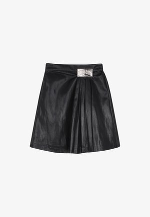 Minifalda de cuero negro con pliegues y una placa rectangular de logo metálico plateado en la cinturilla.