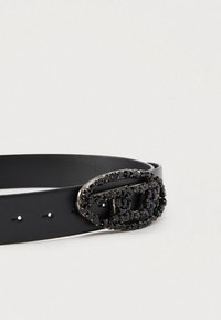 Melnas ādas josta ar ovālu sprādzi, rotātu ar melniem rhinestones. Gluda tekstūra, vairāki caurumi izmēra regulēšanai.