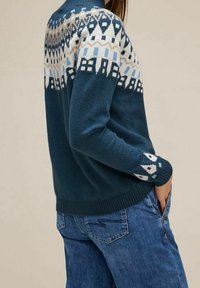 Stickad tröja i mörk teal med ett mönstrat krage i cream och ljusblått. Har ribbade ärmmuddar och nederkant. Bärs med blå denimjeans.