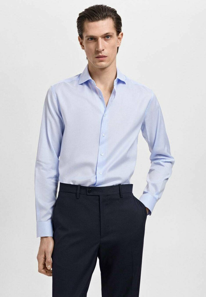 Cămașă bleu deschis, cu un model texturat și o guler clasic, asortată cu pantaloni închiși la culoare. Prezintă mâneci lungi și un design ajustat.