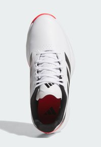 White athletic shoe with black accents and three black stripes, featuring a red heel and textured surface. Laces and perforated details visible.