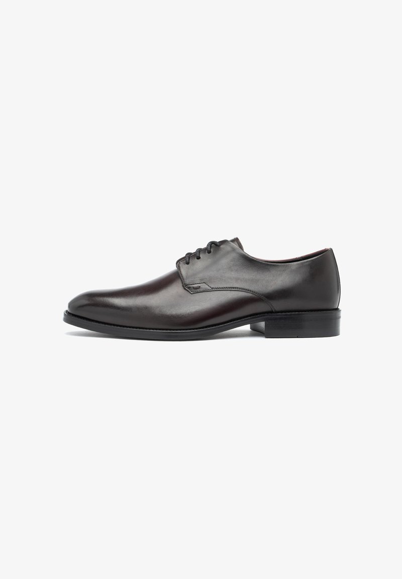 Zapato oxford de cuero marrón con superficie lisa, punta redondeada y cordones. Presenta un tacón bajo y un diseño minimalista.
