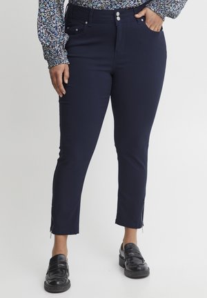 Navy blue fitted pants with a smooth texture, featuring zippers at the ankle and a classic five-pocket design. Buttons at the waist.