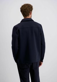 Marineblauwe sweatshirt jas met een kraag, lange mouwen en een gladde textuur; bevat stikseldetails en een logosticker op de mouw.