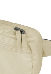 Borsa a vita di tessuto beige con due zip grigie, superficie strutturata e cuciture visibili lungo i bordi. Compatta, con un unico scomparto principale.