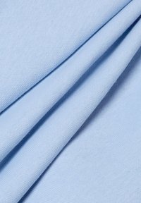 Tessuto azzurro chiaro con una superficie liscia e un delicato motivo di tessitura, drappeggiato in pieghe che rivelano la sua flessibilità e morbidezza.